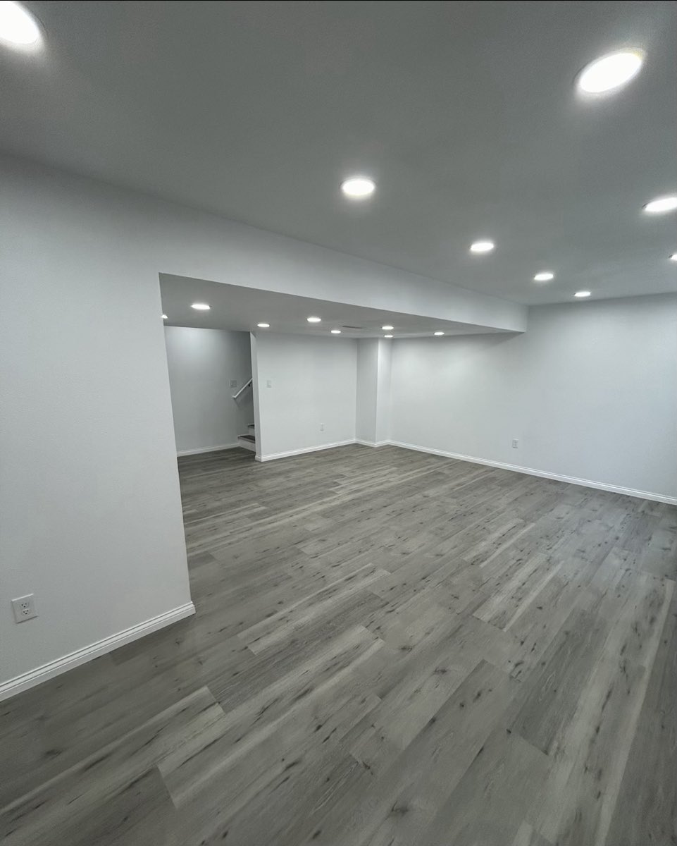 Finished basement with gray luxury vinyl plank flooring, fresh drywall and recessed lighting
