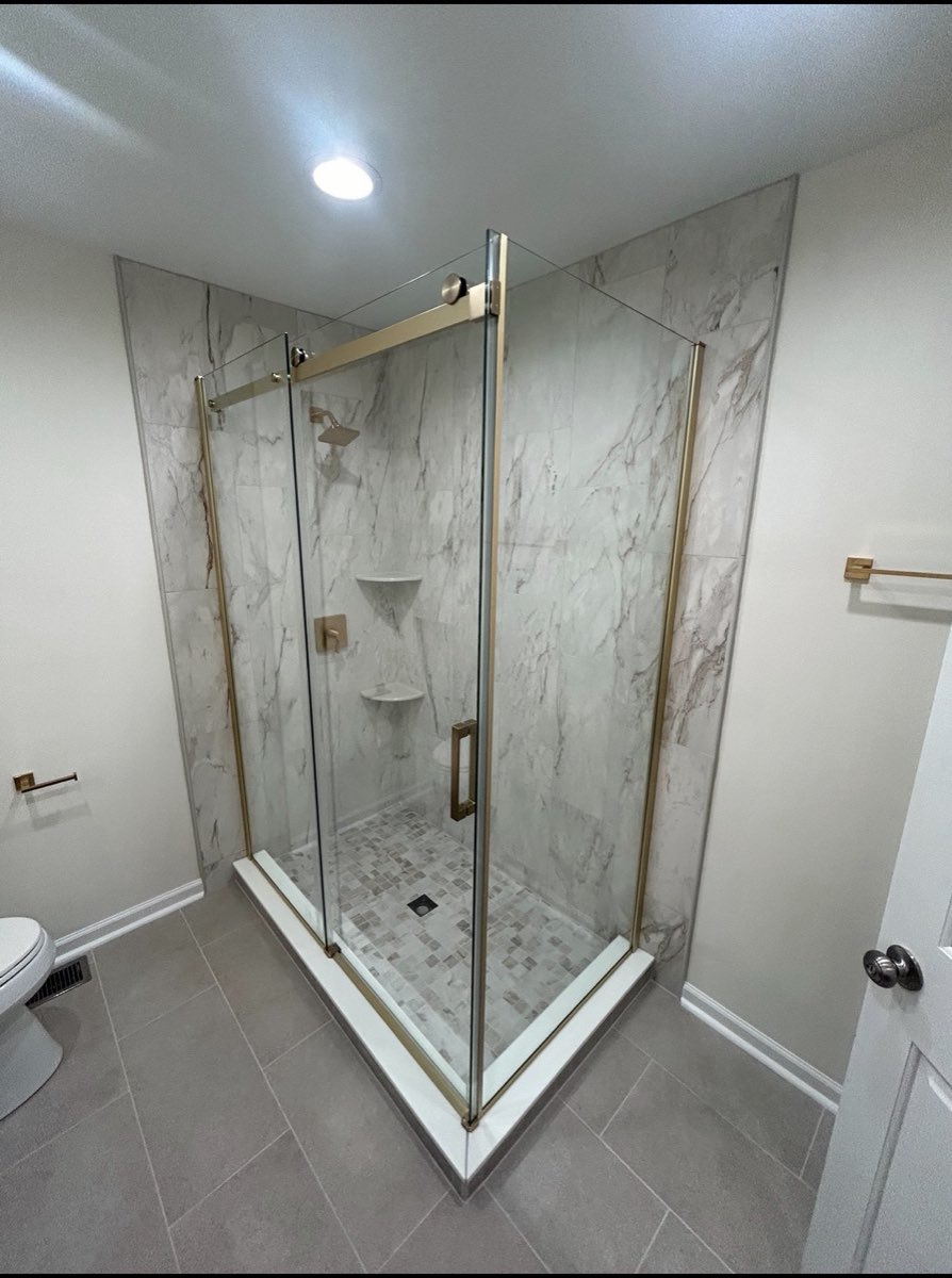 Bathroom remodel with a marble-look corner shower, frameless glass door and brushed-gold trim